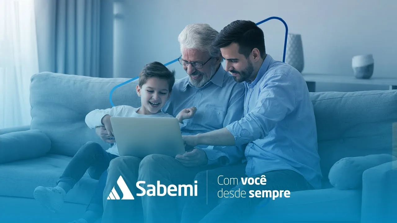 Cena do manifesto Com você desde sempre: avô, pai e filho sorrindo no sofá em frente a um notebook, com a assinatura da Sabemi.